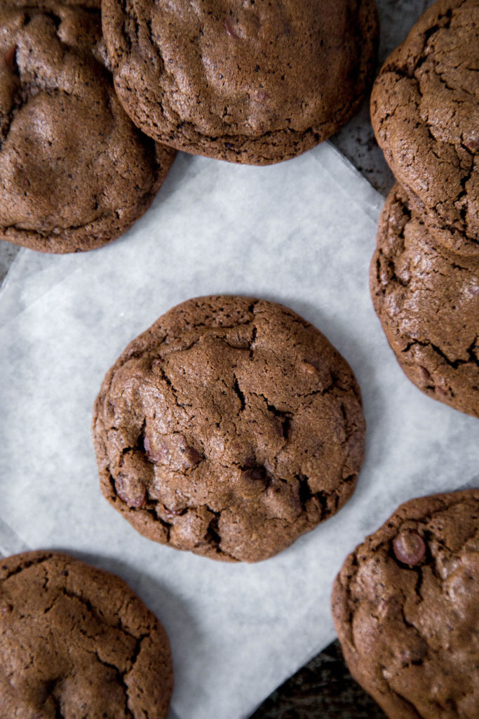 Double chocolate cookies sitting on white parchment paper on a metal cookie sheet