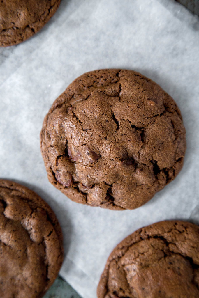 Double chocolate cookies sitting on white parchment paper on a cookie sheet 