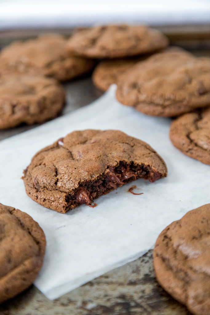 Double chocolate cookies sitting on white parchment paper on a cookie sheet