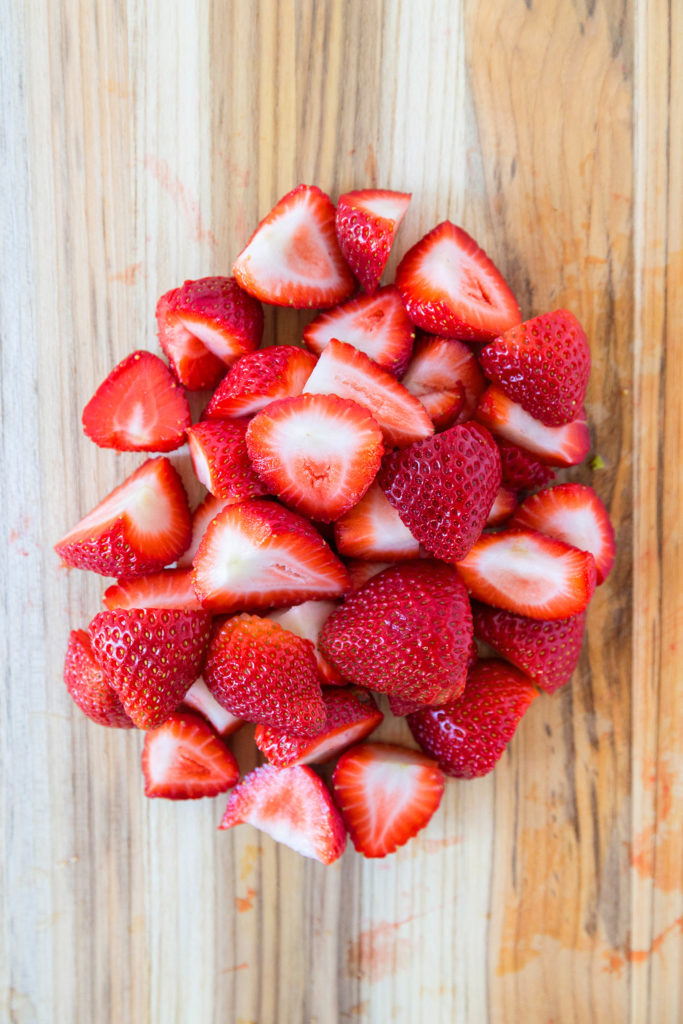 Cut strawberries on a wooden chopping board