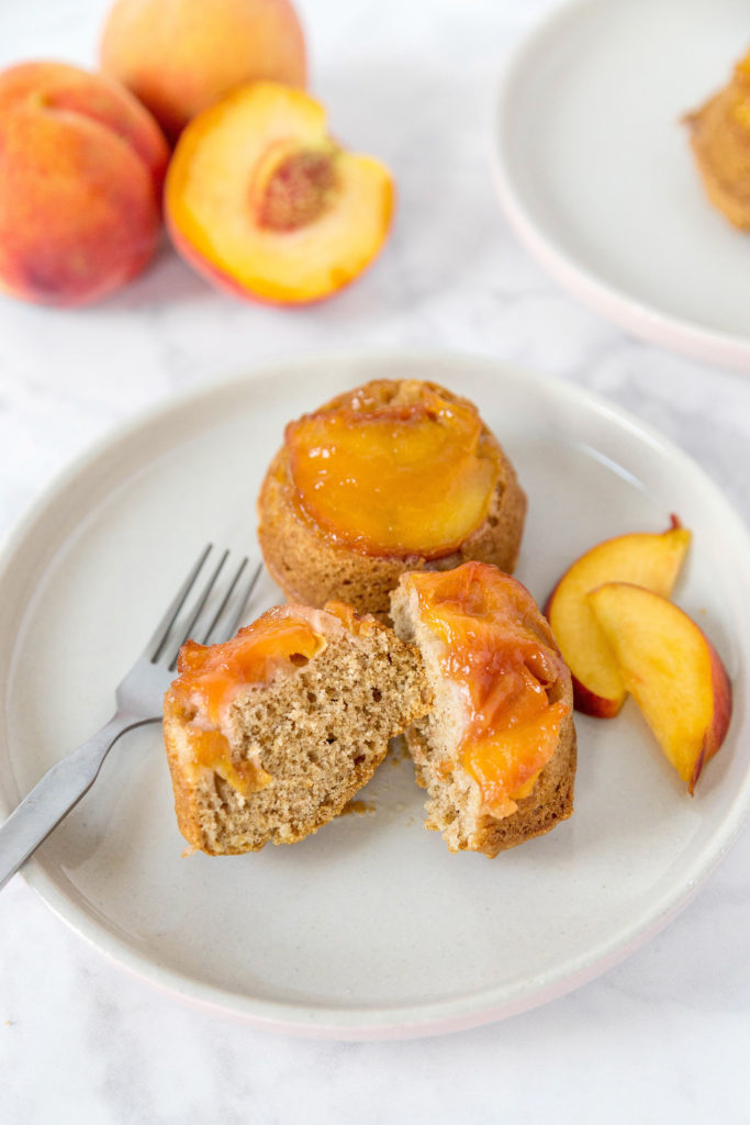 mini peach upside down cakes on a white plate, with one cake cut in half to show cross-section