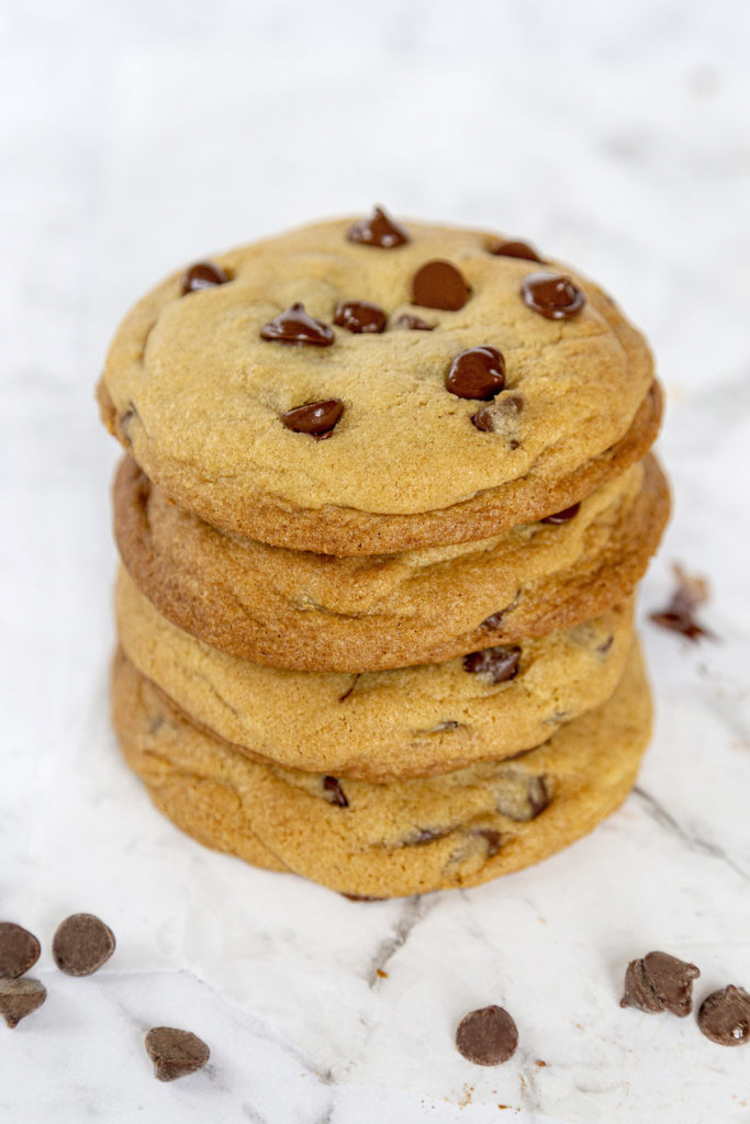 A stack of 4 chocolate chip cookies on a marble background.