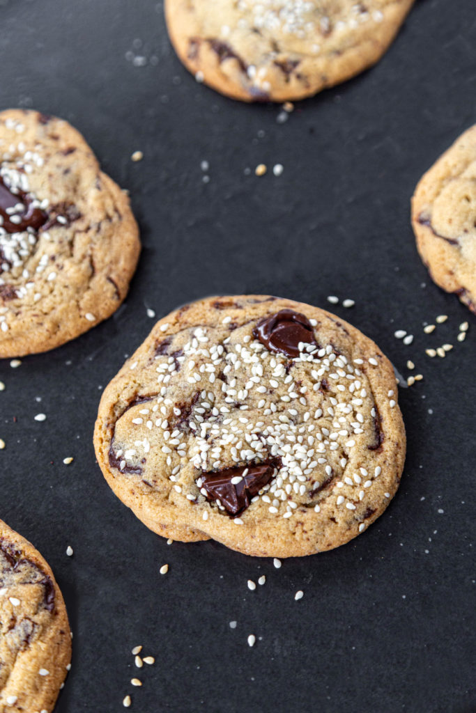 Tahini chocolate chunk cookies sitting on dark grey metal pan