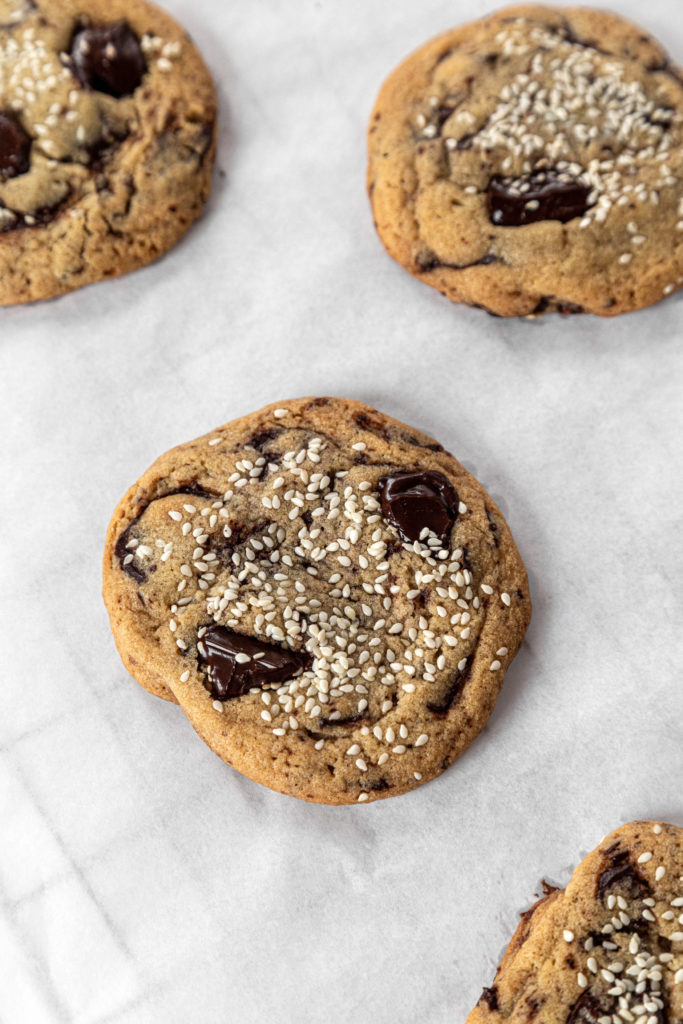 Tahini chocolate chunk cookies sitting on white parchment paper