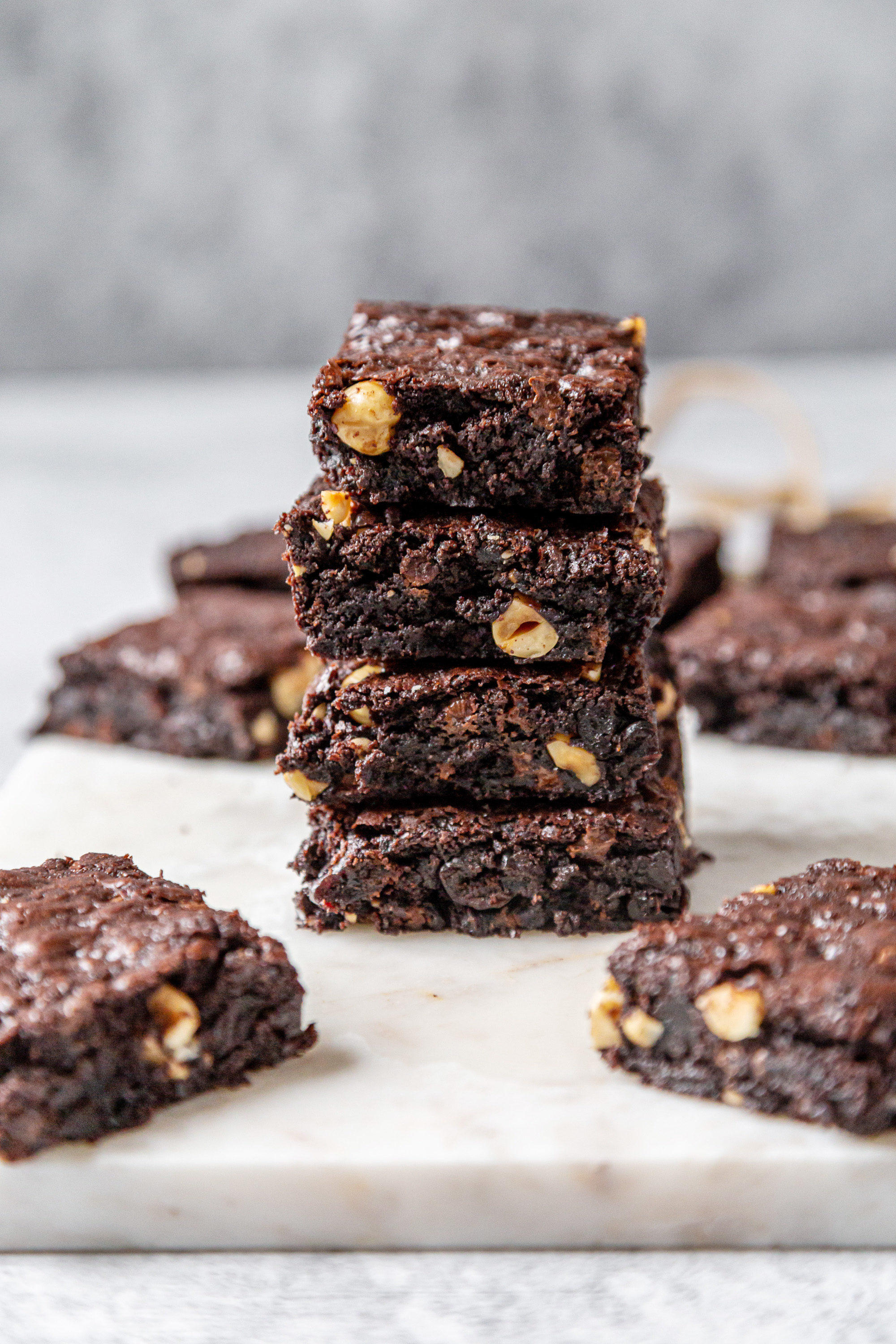 A stack of 4 chocolate brownies with more brownies surrounding the stack