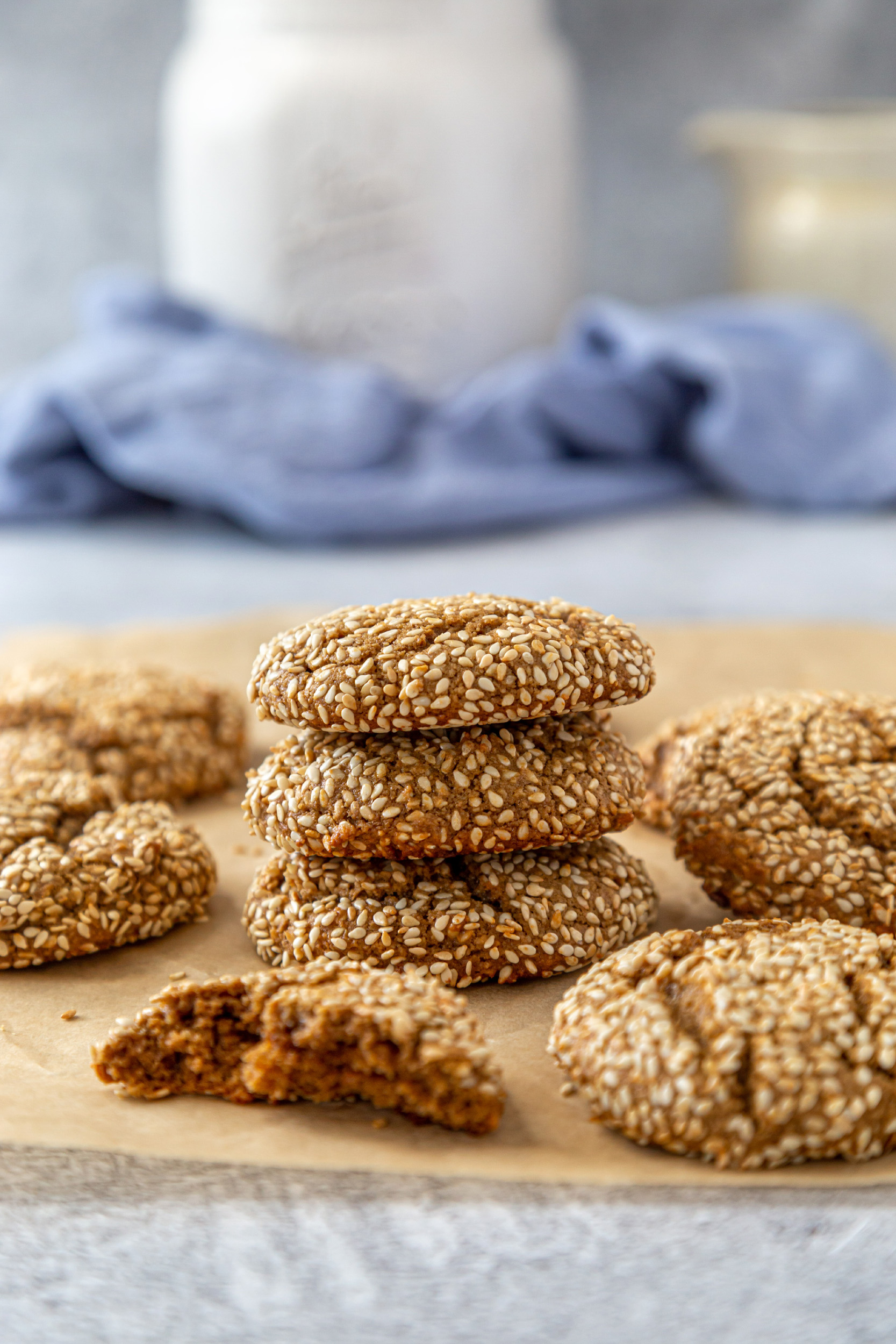 A tower of sesame tahini cookies sitting on brown parchment paper