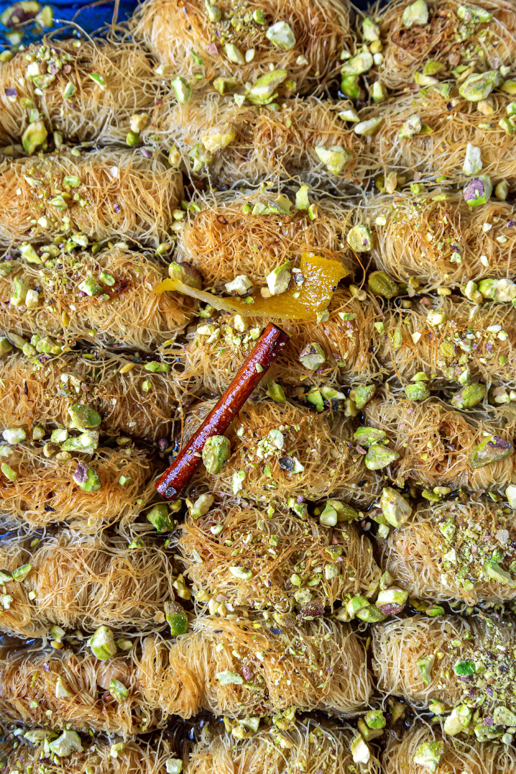 Close up shot of the Kataifi, sprinkled with pistachios, with a cinnamon stick in the center