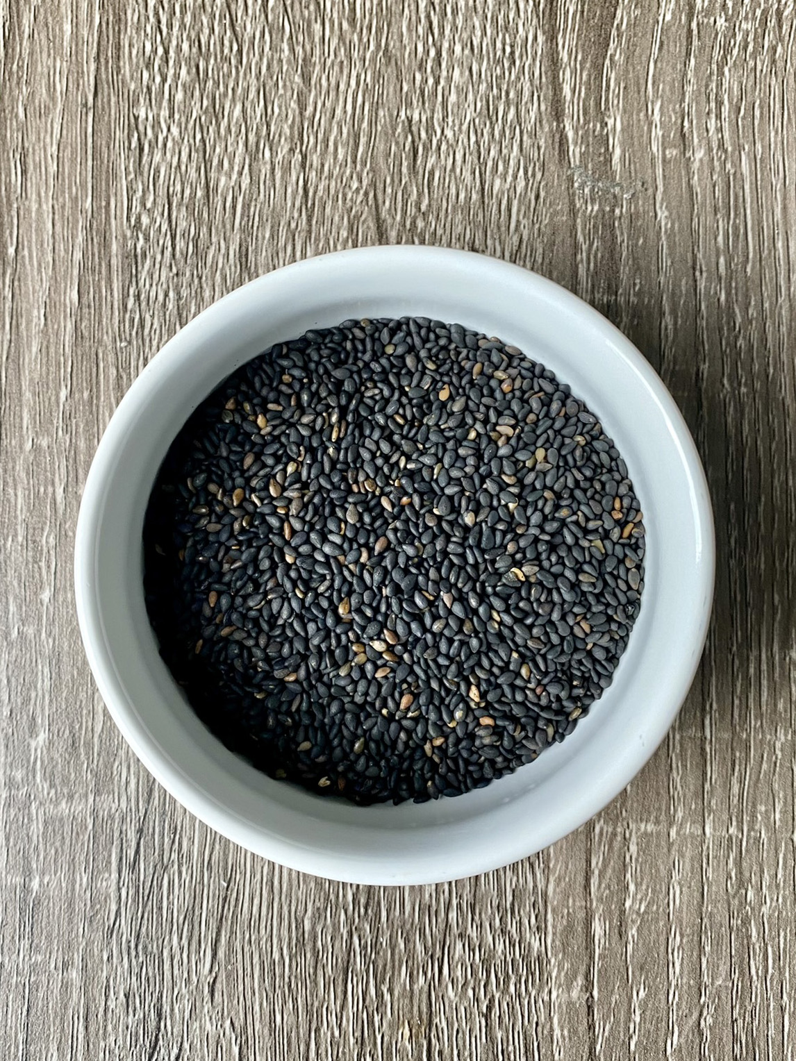 small white bowl filled with black sesame seeds